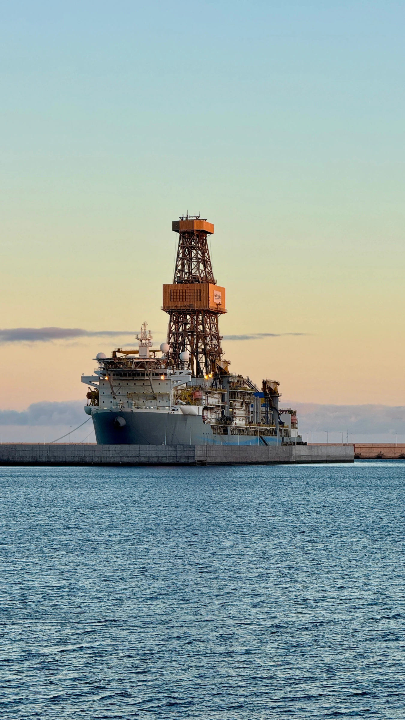A drillship moored in harbour at dusk